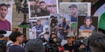 Un portavoz de los medios de comunicación en Barcelona habla en una conferencia de prensa con personas con retratos de los periodistas de Al Jazeera recientemente asesinados en Gaza por el ejército israelí.