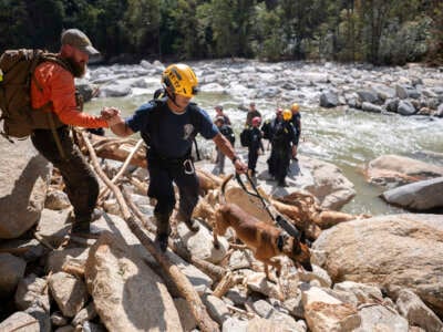 Un miembro del equipo de búsqueda y rescate civil, a la izquierda, da una mano a un miembro de un equipo de búsqueda y rescate urbano de FEMA mientras caminan por el río Broad después del huracán Helene el 2 de octubre de 2024 cerca de Chimney Rock, Carolina del Norte.