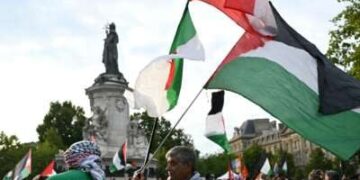 Un hombre sostiene las banderas argelinas (L), libanesas (superiores) y palestinas durante una manifestación pro-palestina contra las acciones de Israel y la hambruna en curso en la Franja de Gaza, y para dar la bienvenida a los activistas liberados de la Liberación de la Freedom Flotilla en el lugar de la République en París, Francia, el 29 de julio de 2025.