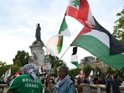 Un hombre sostiene las banderas argelinas (L), libanesas (superiores) y palestinas durante una manifestación pro-palestina contra las acciones de Israel y la hambruna en curso en la Franja de Gaza, y para dar la bienvenida a los activistas liberados de la Liberación de la Freedom Flotilla en el lugar de la République en París, Francia, el 29 de julio de 2025.