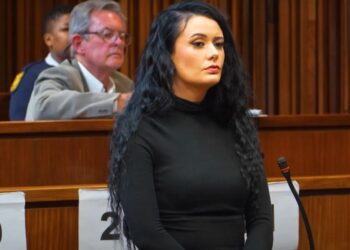 Mujer en la parte superior negra sentada en una sala del tribunal.