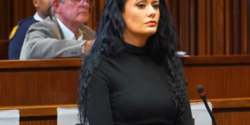 Mujer en la parte superior negra sentada en una sala del tribunal.