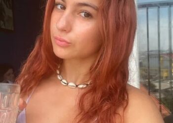 Mujer con cabello rojo en un balcón, disfrutando de un café durante su tiempo enseñando inglés en Vietnam.