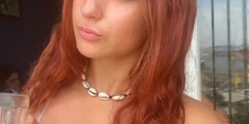 Mujer con cabello rojo en un balcón, disfrutando de un café durante su tiempo enseñando inglés en Vietnam.