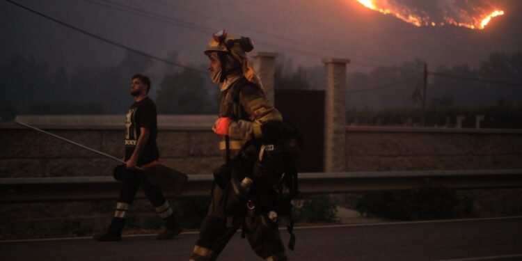 Los bomberos caminan cerca de un gran incendio forestal.
