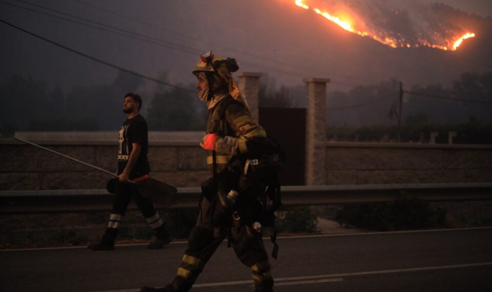 Los bomberos caminan cerca de un gran incendio forestal.