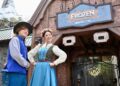 Los miembros del elenco de Hong Kong Disneyland con trajes de temática congelada frente a la entrada de Rele Ride Frozen Ever After.
