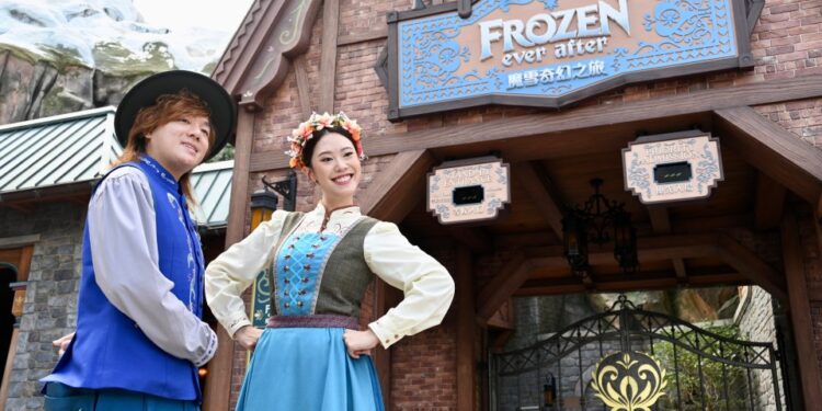 Los miembros del elenco de Hong Kong Disneyland con trajes de temática congelada frente a la entrada de Rele Ride Frozen Ever After.