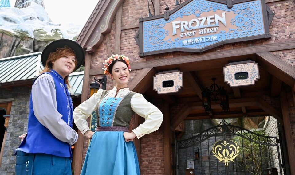 Los miembros del elenco de Hong Kong Disneyland con trajes de temática congelada frente a la entrada de Rele Ride Frozen Ever After.