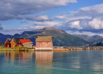 Coloridas cabañas de madera en la isla de Sommaroy, Noruega, con montañas en el fondo.