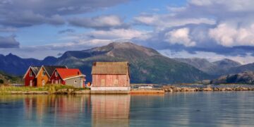 Coloridas cabañas de madera en la isla de Sommaroy, Noruega, con montañas en el fondo.