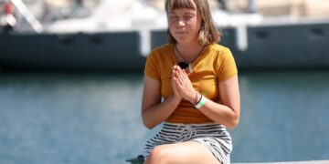 Greta Thunberg se sienta en un bote, con los ojos cerrados, las manos juntas.