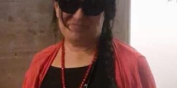 Foto de una mujer con gafas de sol y un cárdigan rojo.