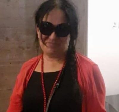 Foto de una mujer con gafas de sol y un cárdigan rojo.