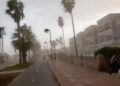 La gente que corre por un camino de la playa durante una fuerte tormenta de viento.