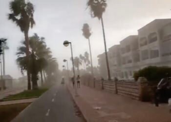 La gente que corre por un camino de la playa durante una fuerte tormenta de viento.