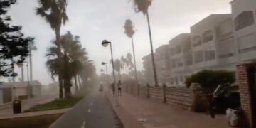 La gente que corre por un camino de la playa durante una fuerte tormenta de viento.
