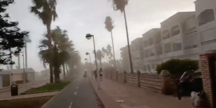 La gente que corre por un camino de la playa durante una fuerte tormenta de viento.
