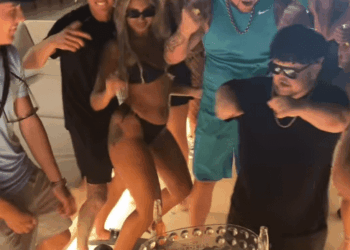 Grupo de personas que bailan alrededor de un refrigerador de bebidas.