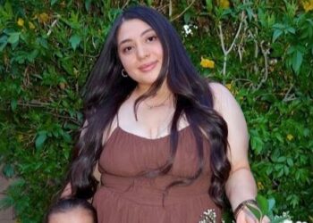 Mujer y niño pequeño posando con una canasta de flores.