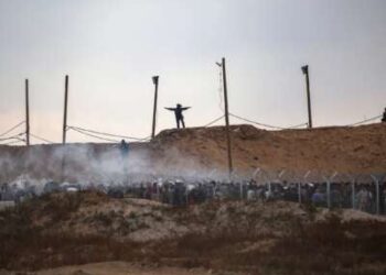 Miembros de una empresa privada de seguridad estadounidense, contratada por la Fundación Humanitaria de Gaza (GHF), palestinos desplazados directos mientras se reúnen para recibir suministros de ayuda en un centro de distribución en la Franja Central de Gaza el 8 de junio de 2025, ya que las tropas israelíes disparan bombas de humo.