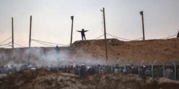 Miembros de una empresa privada de seguridad estadounidense, contratada por la Fundación Humanitaria de Gaza (GHF), palestinos desplazados directos mientras se reúnen para recibir suministros de ayuda en un centro de distribución en la Franja Central de Gaza el 8 de junio de 2025, ya que las tropas israelíes disparan bombas de humo.