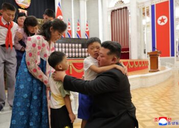 Kim Jong Un abrazando a los hijos de soldados caídos en una ceremonia de premiación.