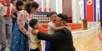 Kim Jong Un abrazando a los hijos de soldados caídos en una ceremonia de premiación.
