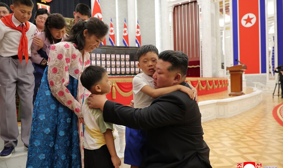 Kim Jong Un abrazando a los hijos de soldados caídos en una ceremonia de premiación.