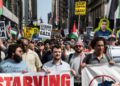 Un grupo de manifestantes dirigidos por Mahmoud Khalil Hold Signs que decían "Stand with Gaza" en la ciudad de Nueva York