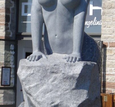 Estatua de una sirena sentada en una roca.