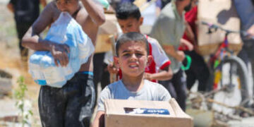 Un niño lleva una caja de suministros de alivio de la Fundación Humanitaria de Gaza (GHF) a medida que los palestinos desplazados regresan de un centro de distribución de ayuda en la Franja Central de Gaza el 29 de mayo de 2025.