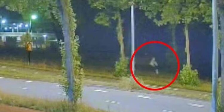 Imágenes de la cámara de seguridad nocturna de una persona que corre a lo largo de una carretera.