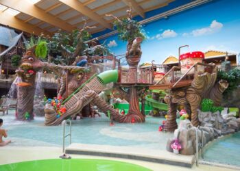 Área de juego acuático infantil con esculturas caprichosas de árboles y hongos.