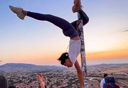 Mujer realizando una parada de manos en una asta de asta en Capadocia, Turquía.