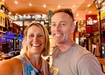 Pareja sonriendo por una selfie en un mercado interior temático.