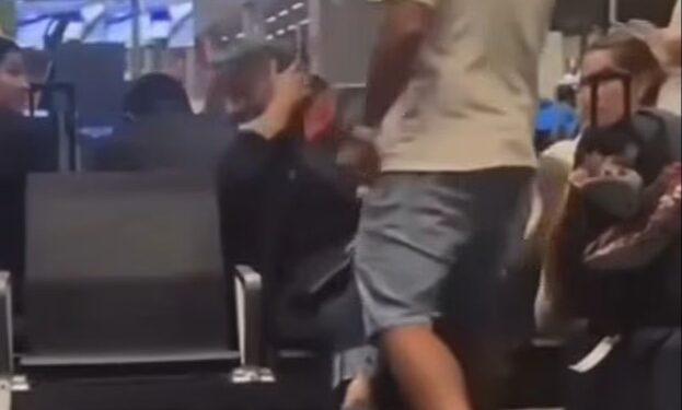 Un hombre golpeando a una mujer en una terminal del aeropuerto.