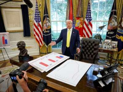 El presidente Donald Trump habla frente a los carteles que representan datos de ingresos familiares en la Oficina Oval el 7 de agosto de 2025.