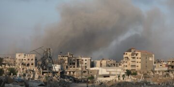 El humo se eleva sobre edificios dañados y un cementerio en la ciudad de Gaza después de ataques aéreos.