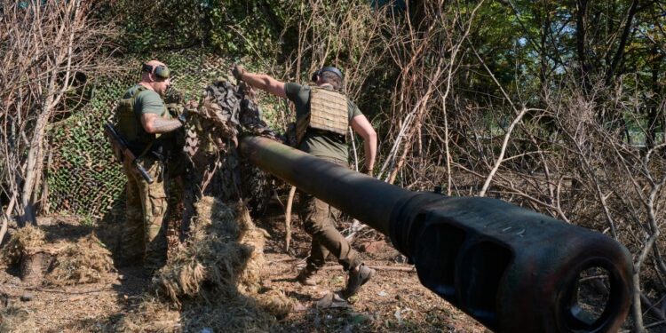 Los soldados ucranianos camufla un obús.