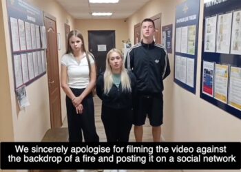 Tres adultos jóvenes de pie en un pasillo de la estación de policía disculpándose por filmar un video.