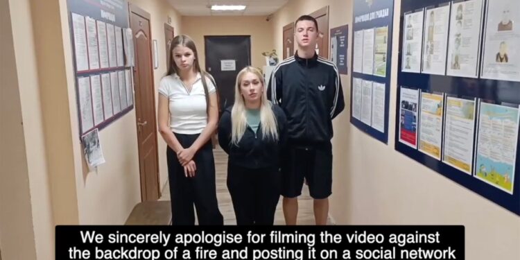 Tres adultos jóvenes de pie en un pasillo de la estación de policía disculpándose por filmar un video.