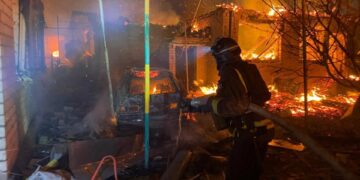 Bombero luchando contra un fuego en un edificio de apartamentos dañado.