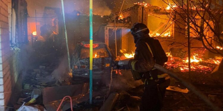 Bombero luchando contra un fuego en un edificio de apartamentos dañado.