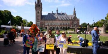 Joie Chowdhury, abogado del Centro de Derecho Ambiental Internacional; Vishal Prasad, director de estudiantes de las Islas del Pacífico que luchan contra el cambio climático; y Jule Schnakenberg, CEO de World's Youth for Climate Justice Pose con señales antes de la sesión de la Corte Internacional de Justicia encargada de emitir la primera opinión de asesoramiento sobre las obligaciones legales de los Estados de abordar el cambio climático, en La Haya, el 23 de julio de 2025.