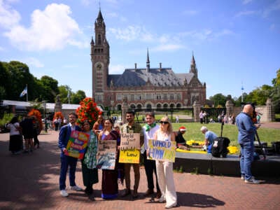 Joie Chowdhury, abogado del Centro de Derecho Ambiental Internacional; Vishal Prasad, director de estudiantes de las Islas del Pacífico que luchan contra el cambio climático; y Jule Schnakenberg, CEO de World's Youth for Climate Justice Pose con señales antes de la sesión de la Corte Internacional de Justicia encargada de emitir la primera opinión de asesoramiento sobre las obligaciones legales de los Estados de abordar el cambio climático, en La Haya, el 23 de julio de 2025.