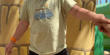 Niño pequeño sosteniendo la mano de un adulto cerca de los postes inflables.