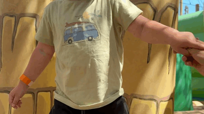 Niño pequeño sosteniendo la mano de un adulto cerca de los postes inflables.