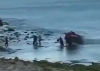 Personas que ayudan a un vehículo atrapado en aguas poco profundas.