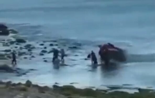 Personas que ayudan a un vehículo atrapado en aguas poco profundas.